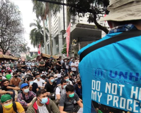 Para pengungsi dari Afghanistan menyampaikan suara mereka sementara polisi mengawasi mereka di depan kantor UNHCR, Jakarta, 24 Agustus 2021. (Foto: VOA/Indra Yoga)