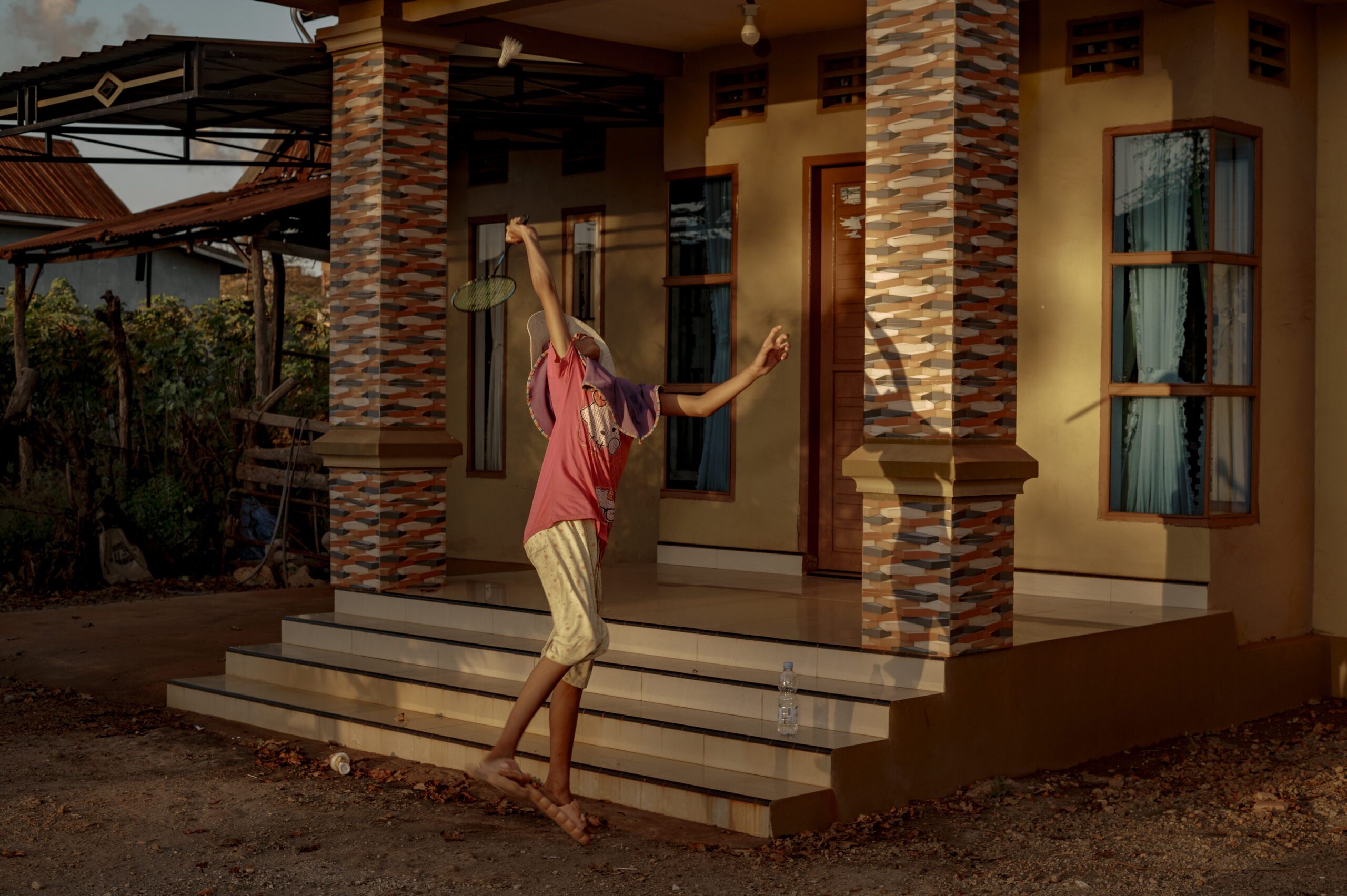 Sri bermain bulutangkis bersama kawannya di halaman rumahnya tanpa menggunakan masker di Dusun Balla Borong, Bantaeng. Anak-anak menjadi kelompok yang paling rentan terkena penyakit akibat polusi pembakaran industri smelter/Iqbal Lubis untuk Bollo.id